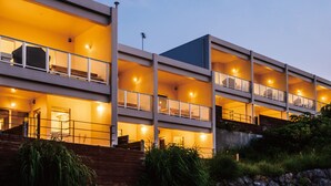 A modern multi-story building with balconies, large windows, and warm lighting. - Private Villa Gushikumui by Coldio Premium (Motobu)
