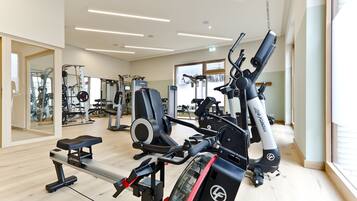 Un gimnasio con diverso equipo de ejercicio, que incluye una máquina de remo, una banca y estaciones de levantamiento de pesas.