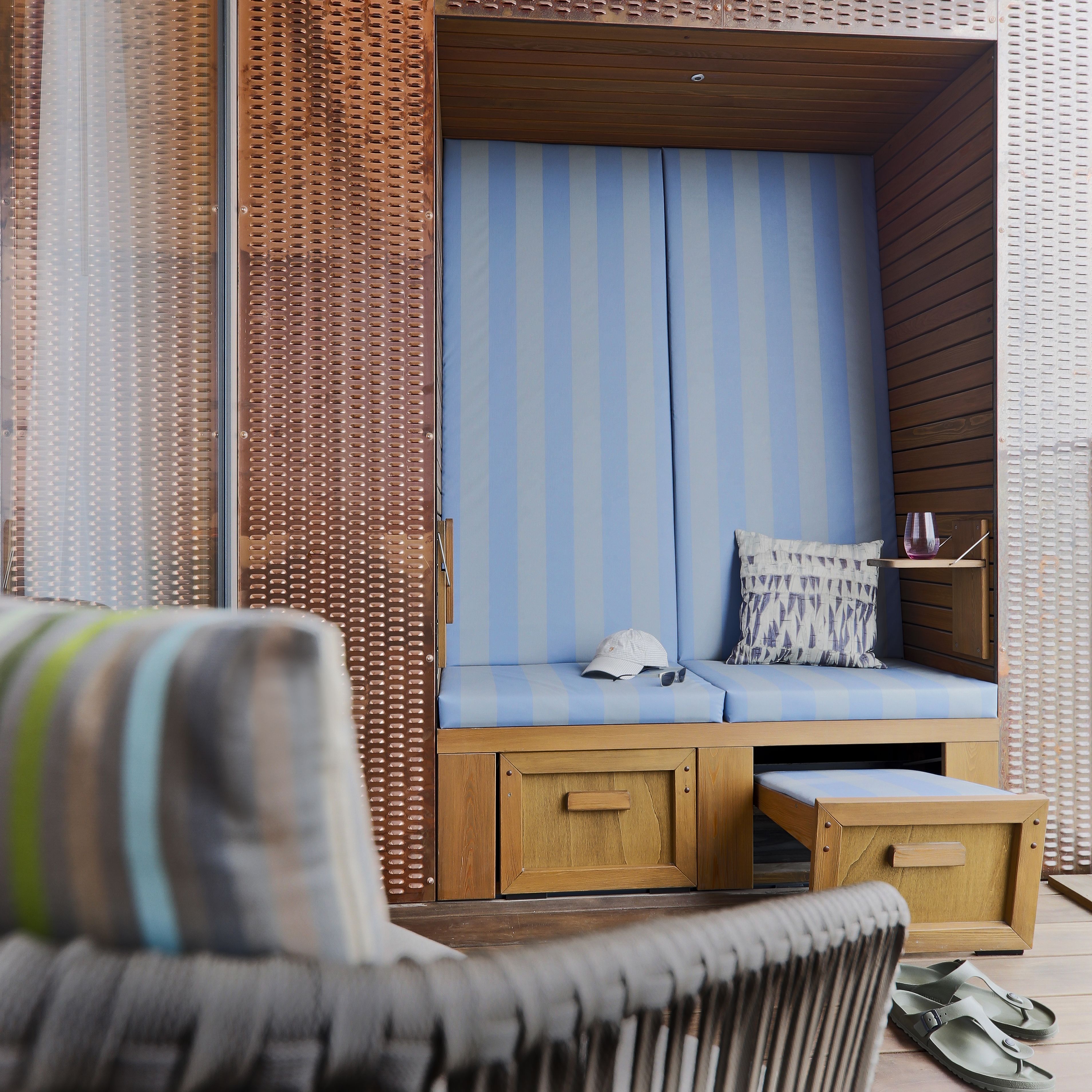 A cozy seating area with a striped cushion, a wooden bench, and a small table.