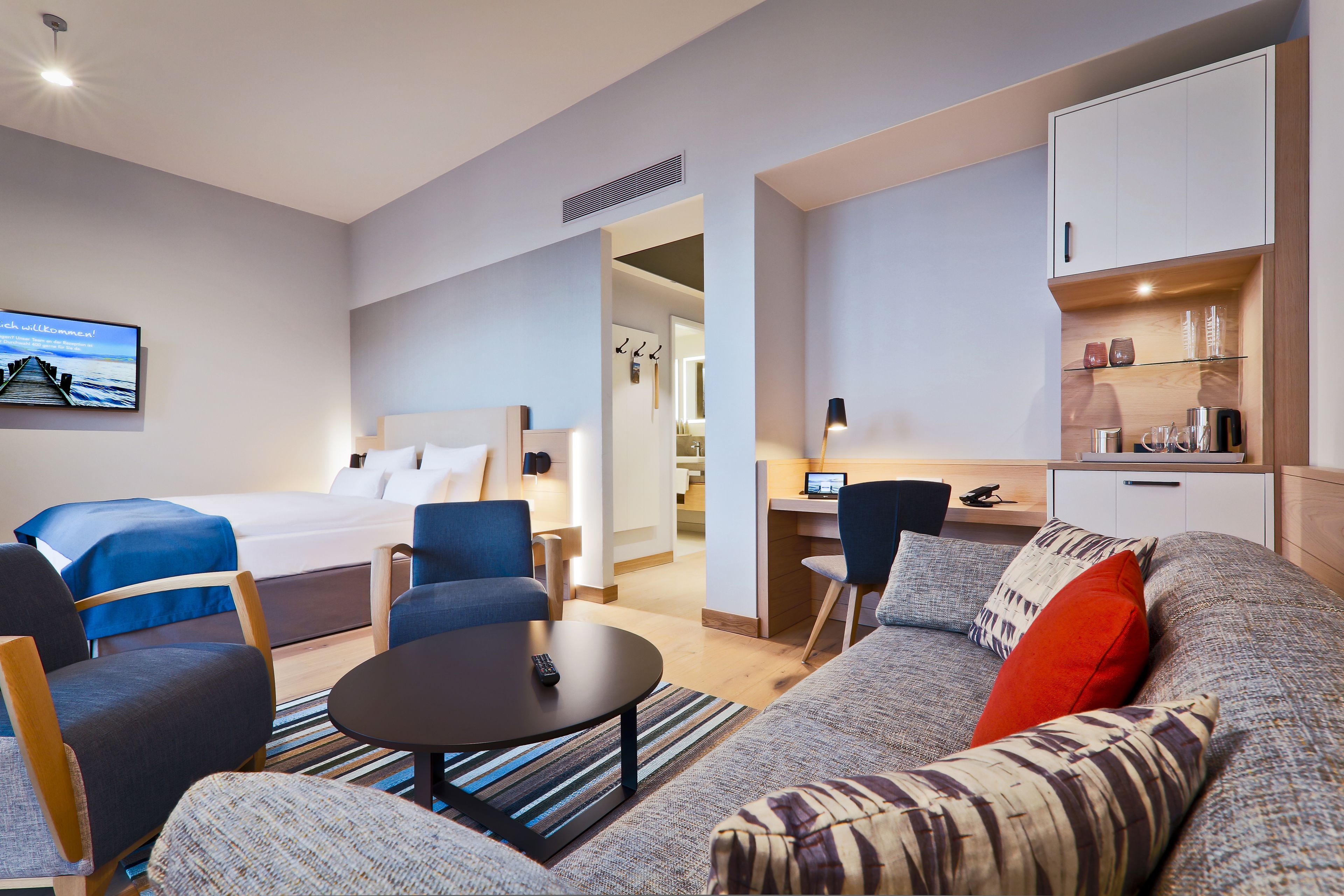 Une chambre d’hôtel moderne équipée d’un lit, d’un canapé, d’un bureau et d’une télévision.