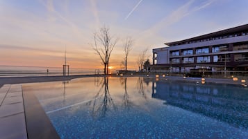 Una piscina techada, una piscina al aire libre, sombrillas