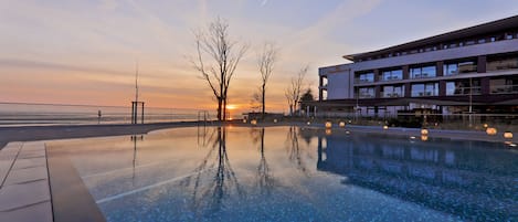 Una piscina techada, una piscina al aire libre, sombrillas