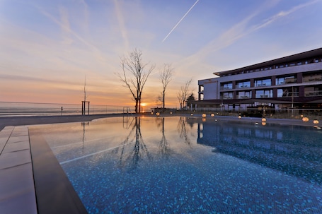 Una piscina techada, una piscina al aire libre, sombrillas