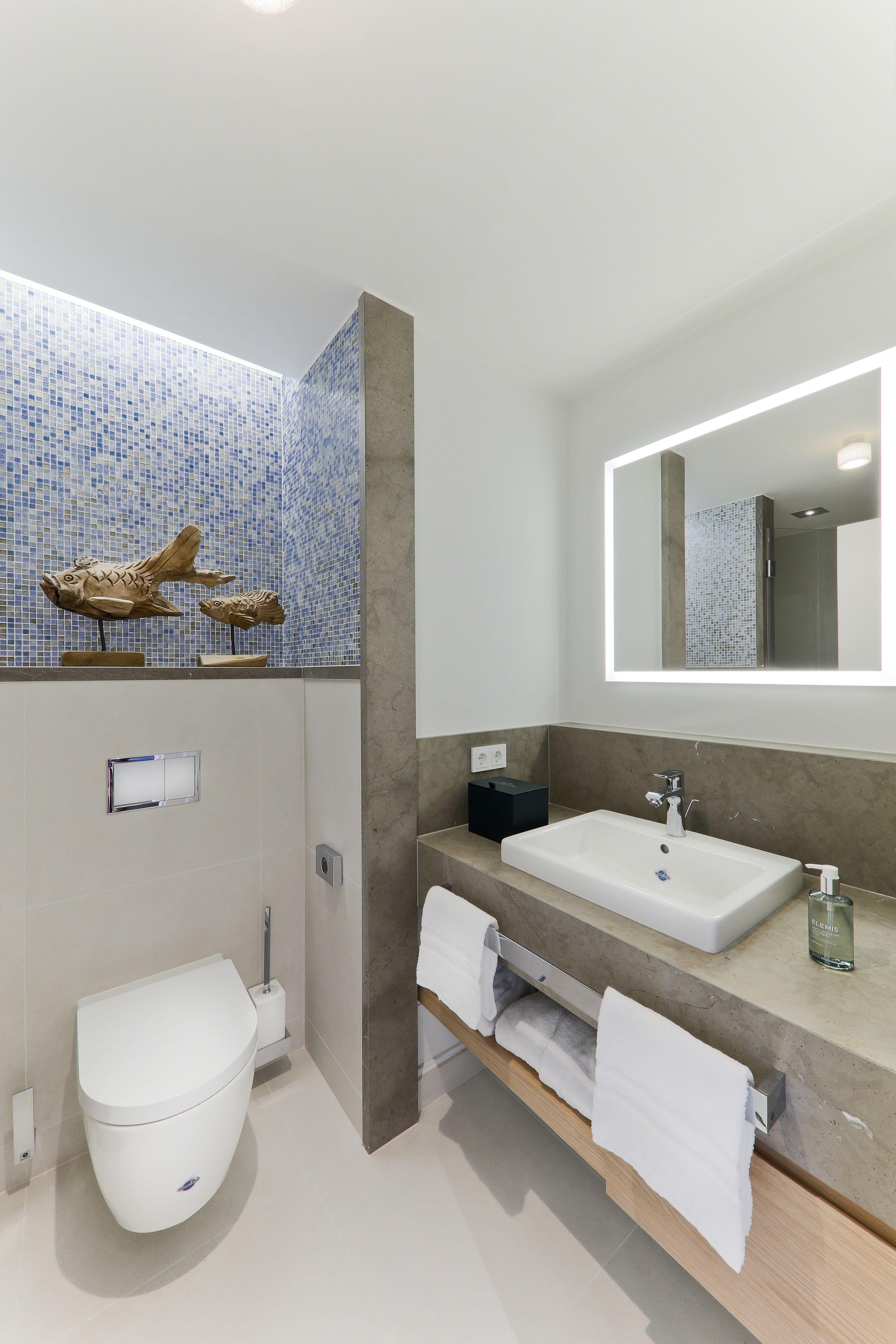 Un bagno moderno con il water, lavandino e specchio.