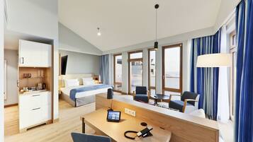 A modern hotel room with a bed, desk, chair, and a small table.