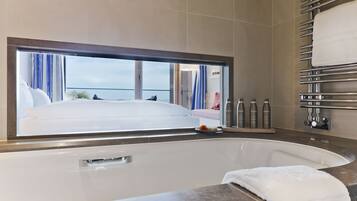 A modern bathroom with a large bathtub, a window with curtains, and a towel rack.