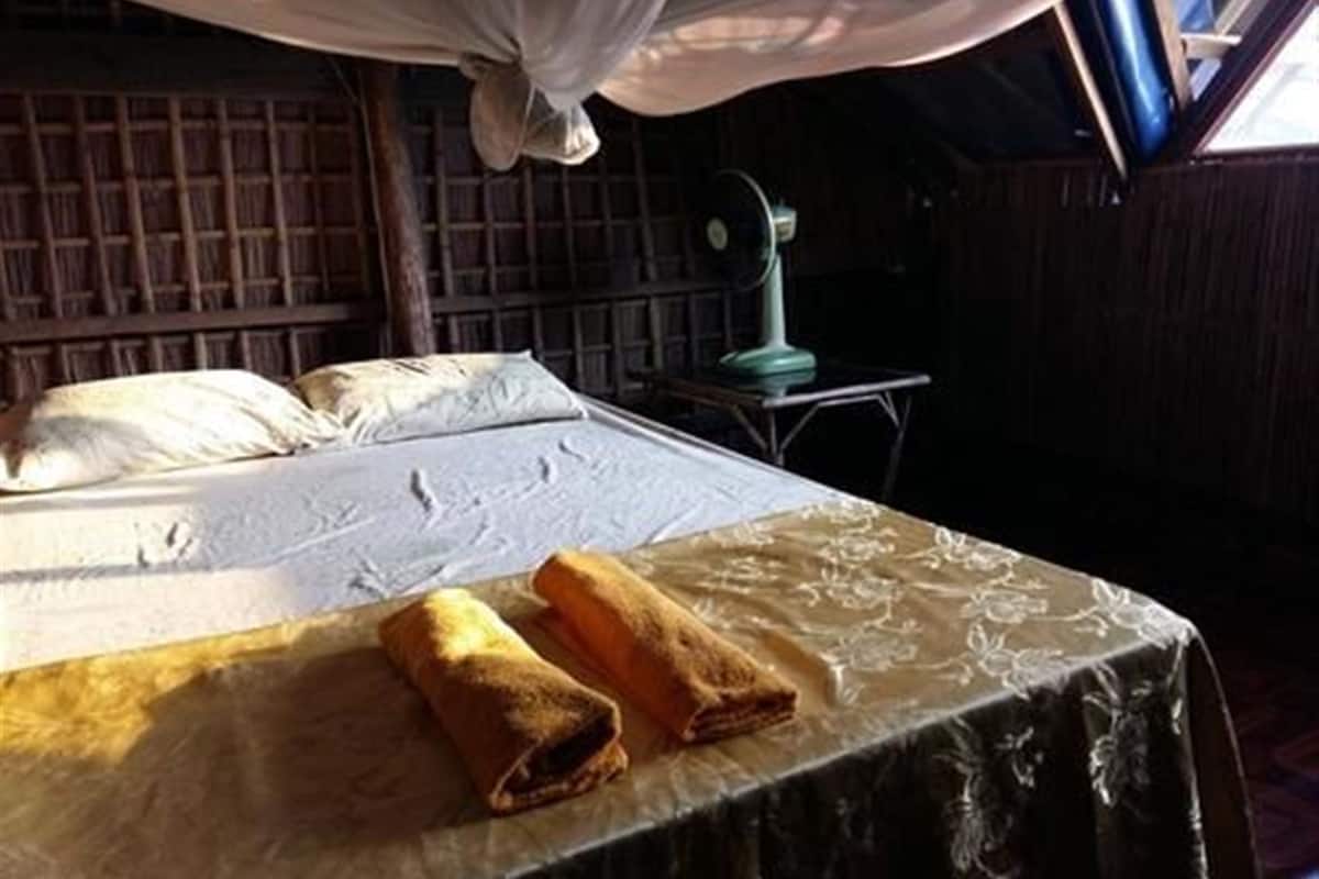 A bed with a canopy, a table with a tablecloth, and a fan.