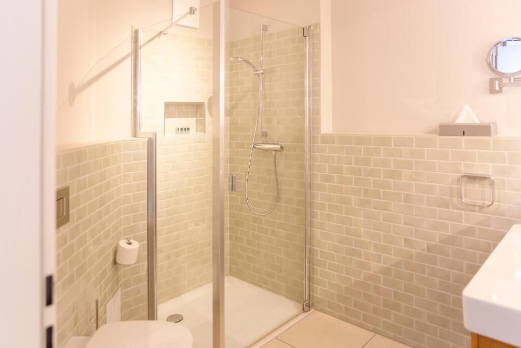 A bathroom with a glass-enclosed shower, a toilet, and a sink.