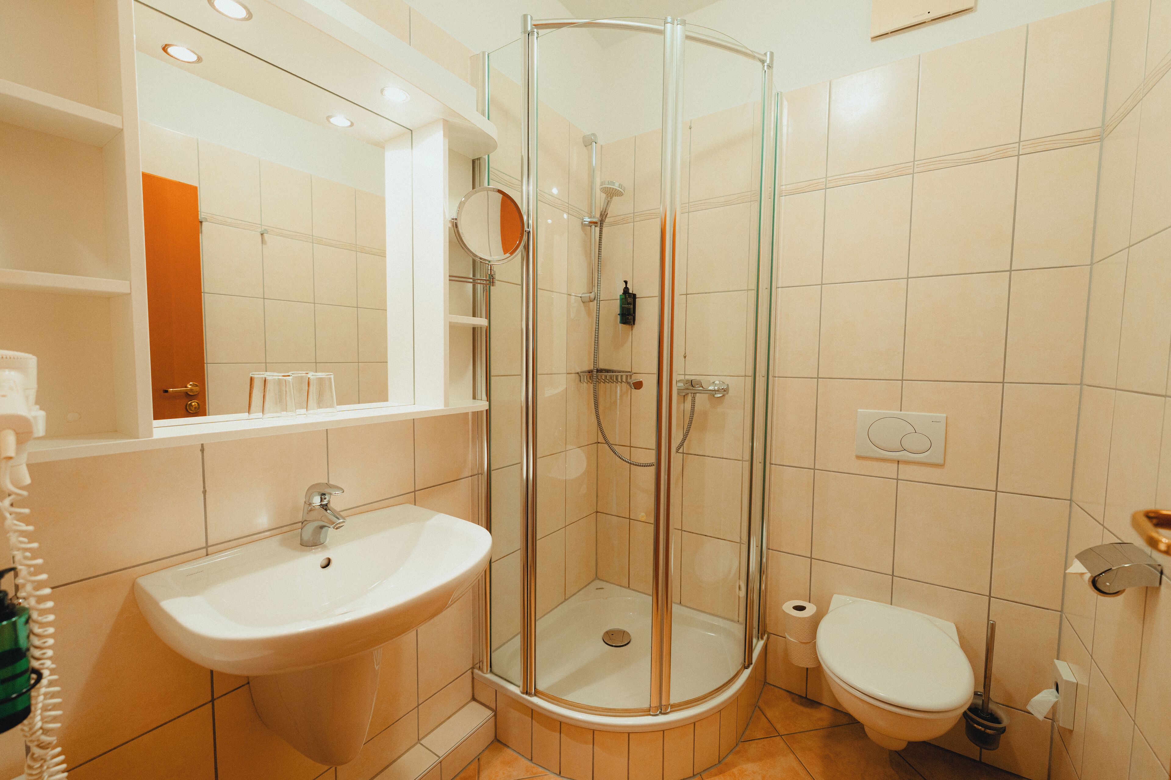 Une salle de bain moderne avec une douche à parois de verre, un lavabo, des toilettes et un miroir.