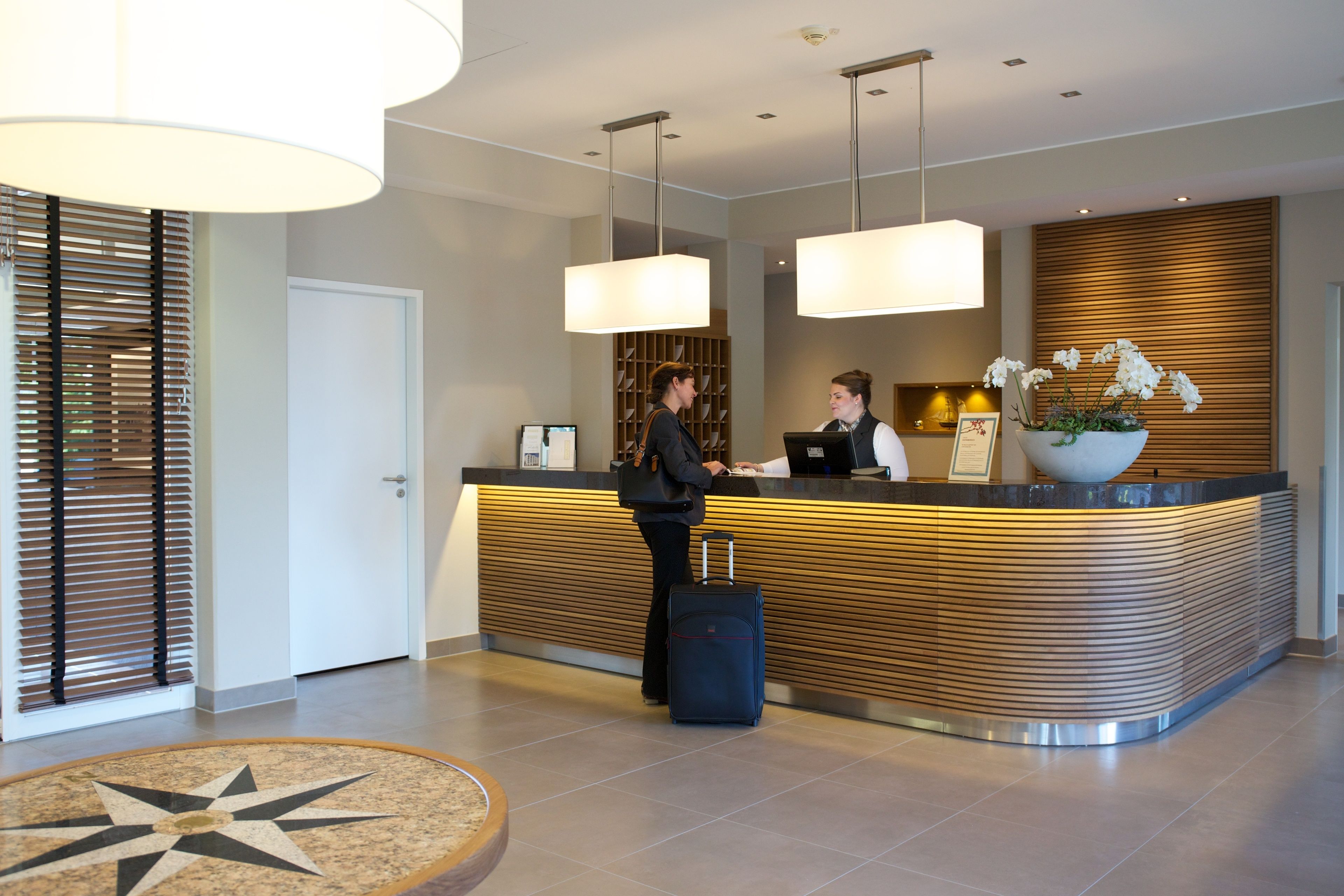 En reception med moderne design, en receptionist og en gæst med bagage.