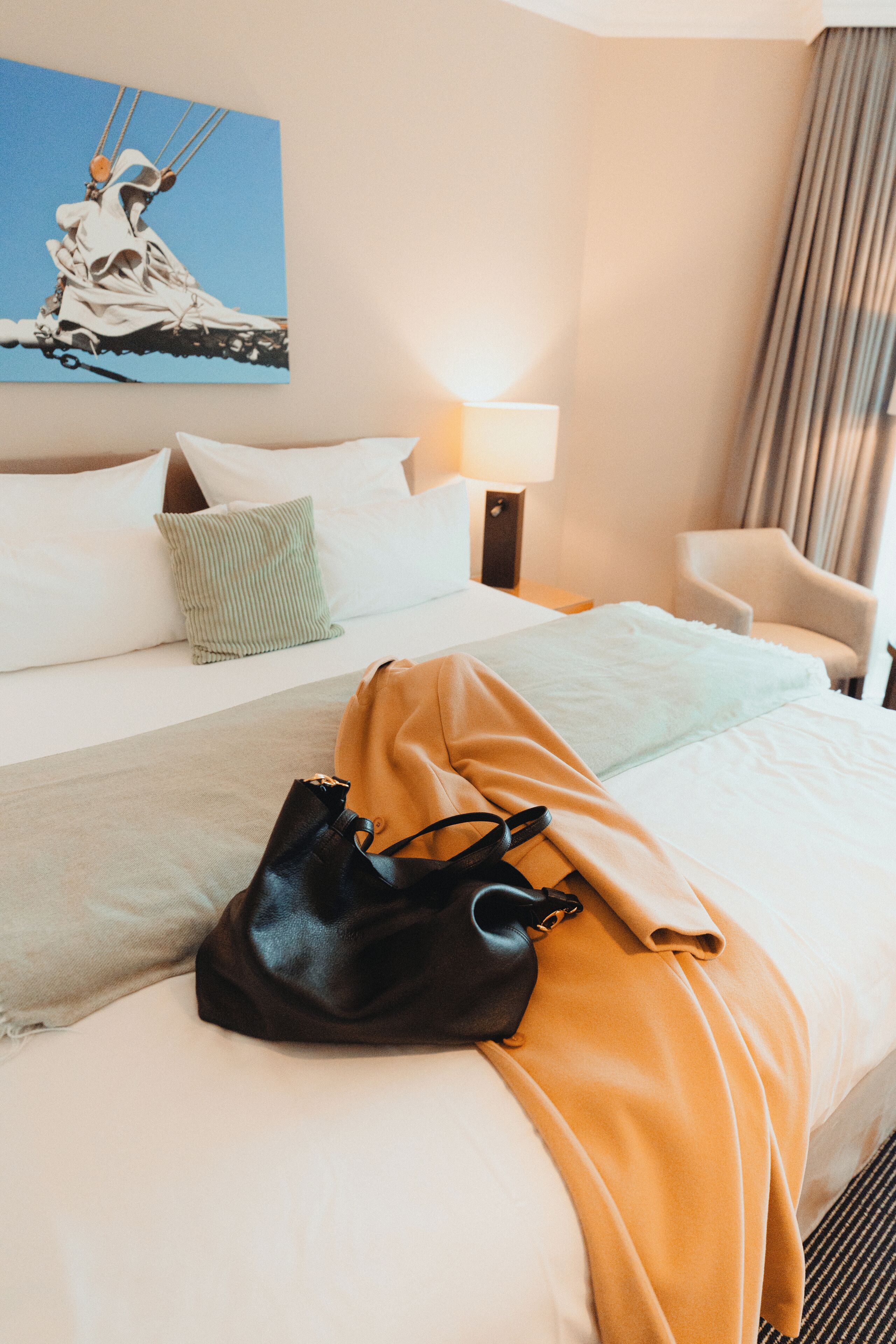 Une chambre d’hôtel avec un lit, une lampe, une chaise et un tableau au mur.