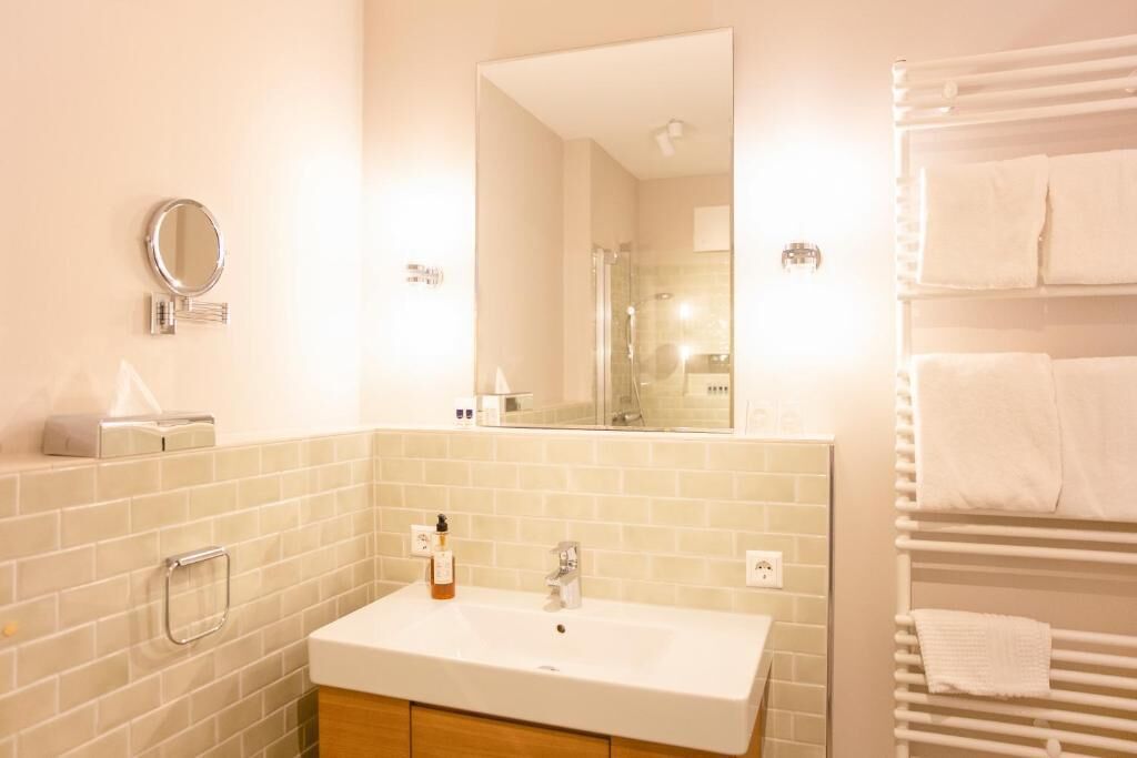 A bathroom with a white sink, a mirror, a towel rack, and a glass shower enclosure.