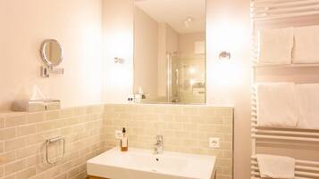 A bathroom with a white sink, a mirror, a towel rack, and a glass shower enclosure.