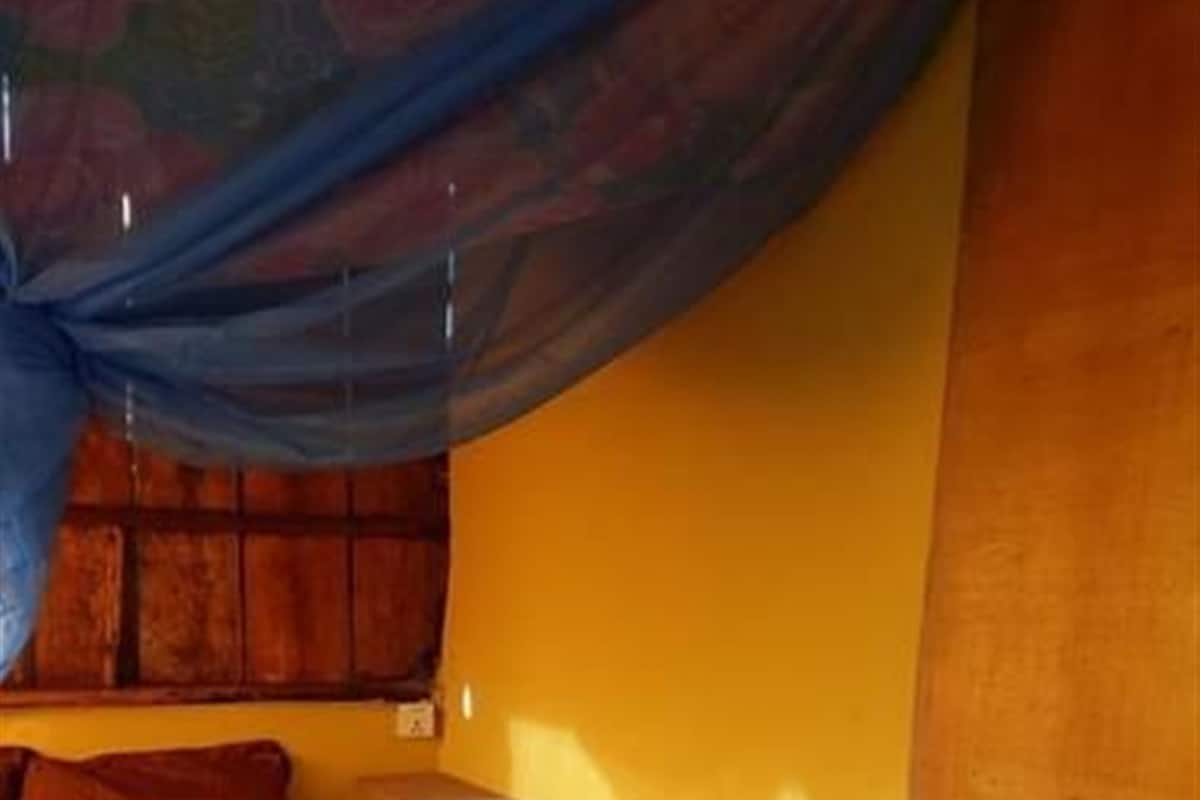 A room with a bed, a small table, and a window with a curtain.