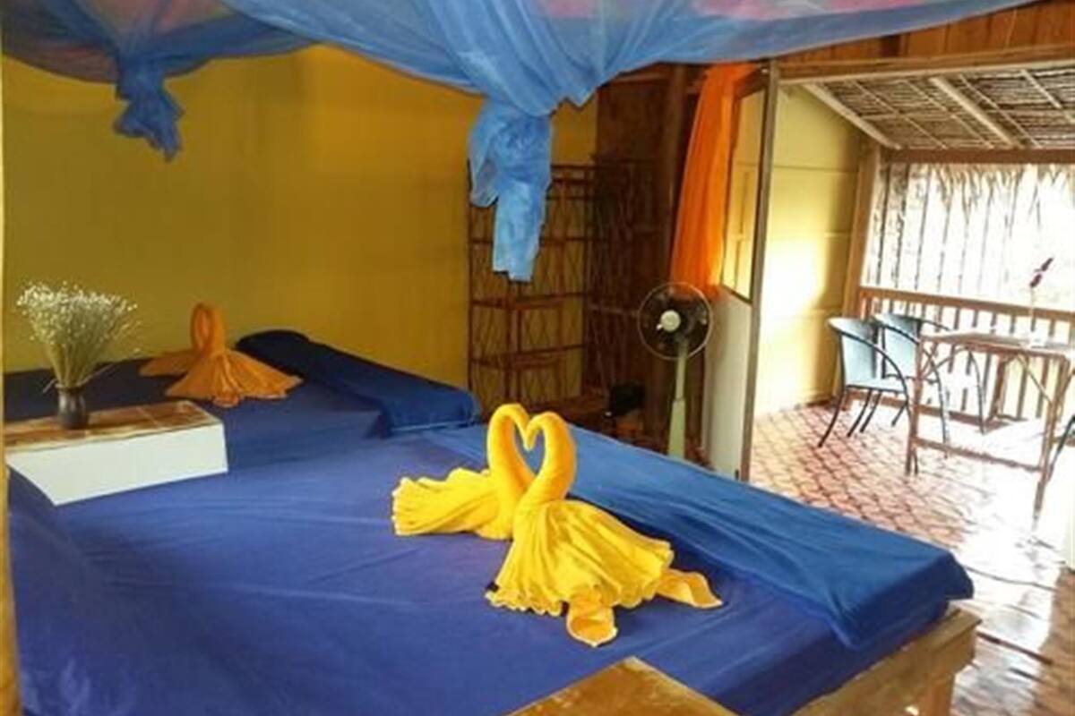 A room with a bed, a fan, and a table with chairs.