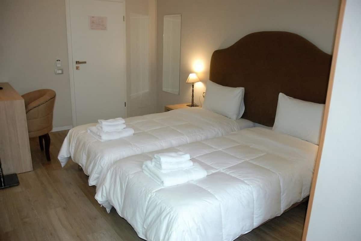 A hotel room with two beds, a desk, and a chair.