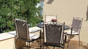 Een terras met een tafel, stoelen, een lamp en een boom.