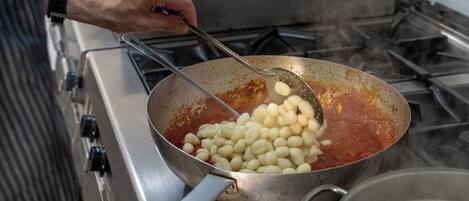 A person cooking gnocchi in a pan on a stove.