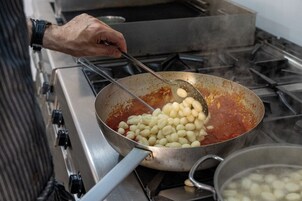 Iemand kookt gnocchi in een pan op het fornuis.