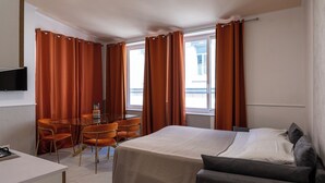 A hotel room with a bed, a sofa, a dining table with chairs, and a TV on the wall. - Hotel San Michele (Naples)