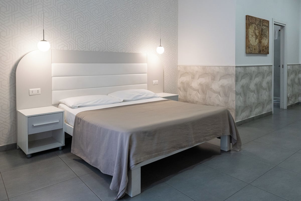 A modern bedroom with a large bed, two bedside tables, and a nightstand.