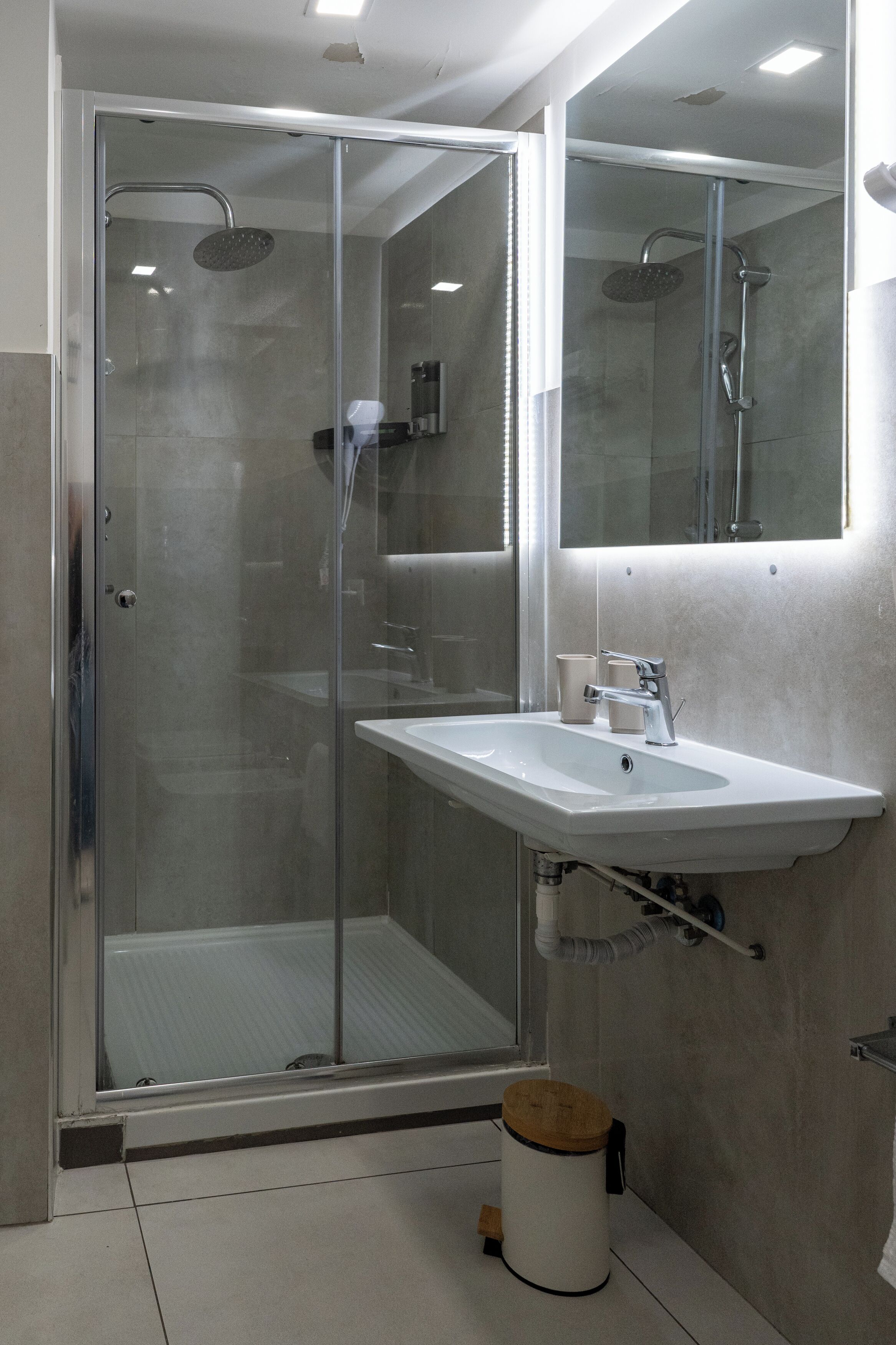 A modern bathroom with a glass-enclosed shower, a white sink, and a mirror above the sink.