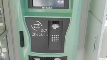 A 24/7 check-in kiosk with a keypad and a screen displaying various icons.