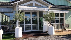 A conservatory with large windows, two potted olive trees, and outdoor seating. - Le 81 Hôtel (Castres)