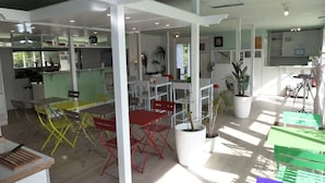 A spacious indoor area with multiple tables and chairs, a kitchen area, and potted plants. - Le 81 Hôtel (Castres)