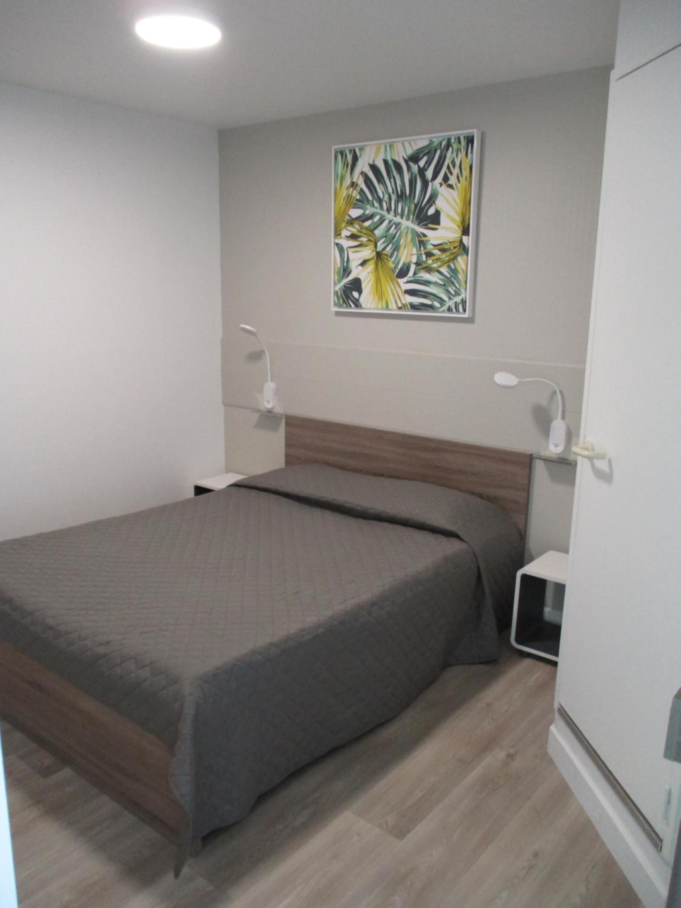 Un dormitorio con cama, mesita de noche y lámpara de pared.