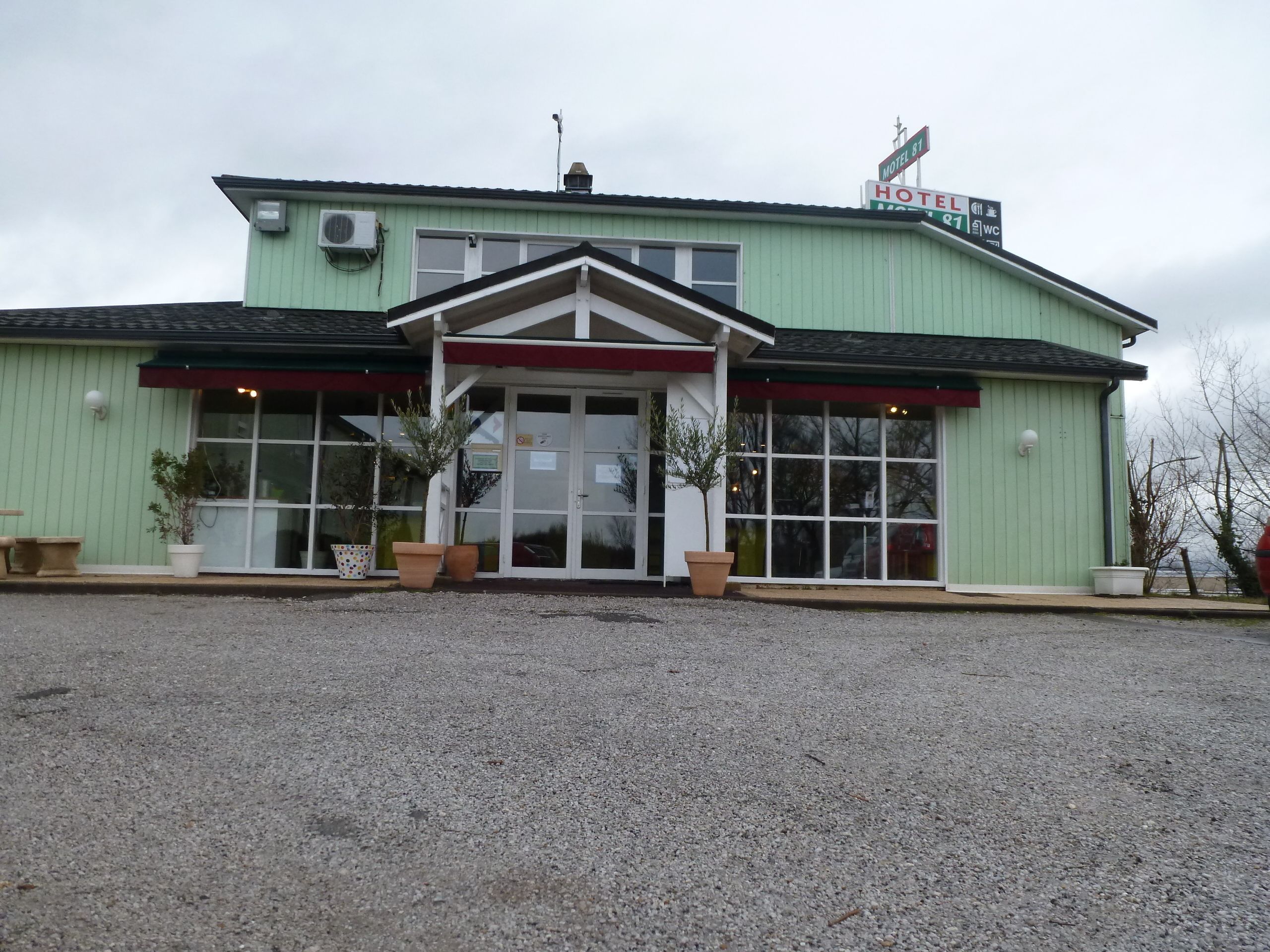 A motel with a green exterior, a red awning, and a sign indicating a single WC.