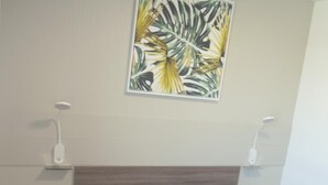 A bedroom with a bed, bedside tables, a wall-mounted light, and a painting. - Le 81 Hôtel (Castres)