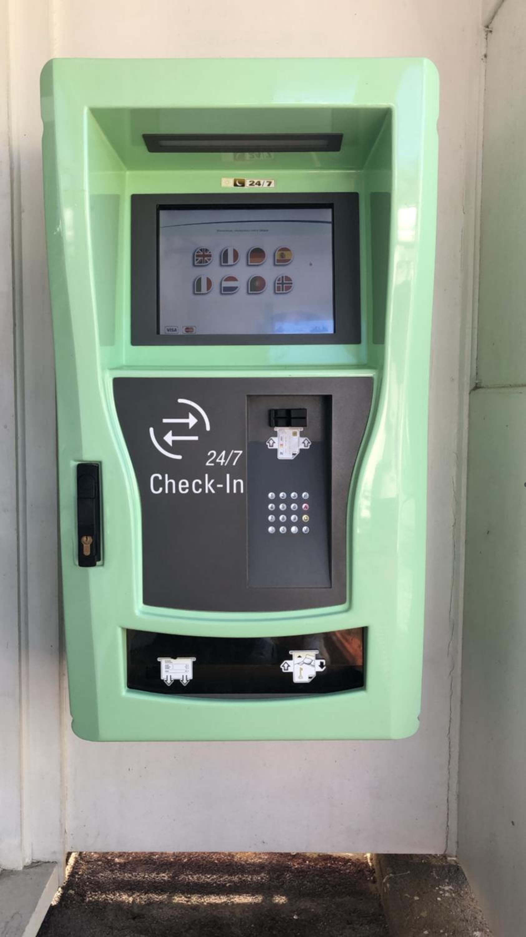 A 24/7 check-in self-service kiosk with a screen displaying various payment options.