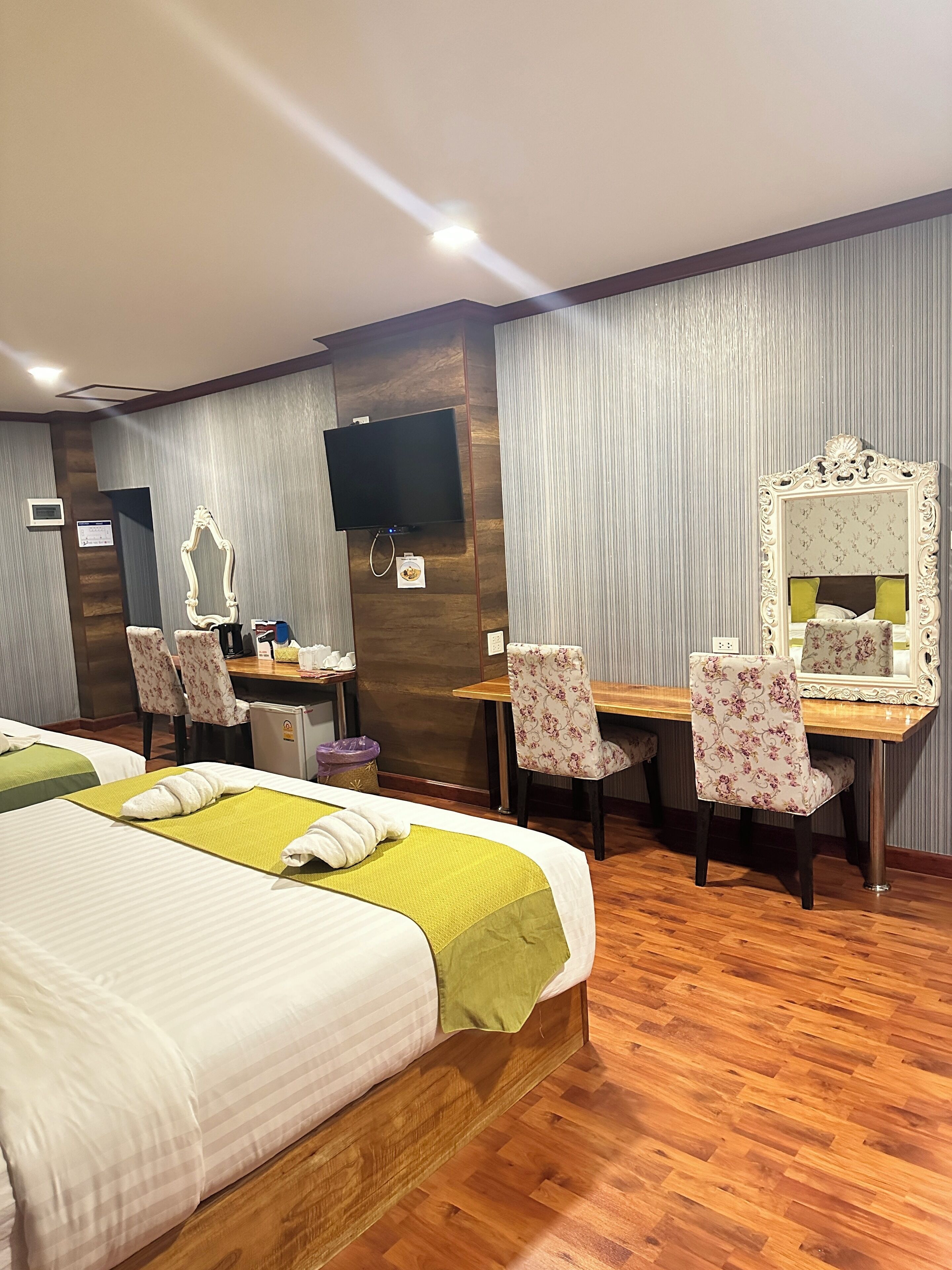 Ein Hotelzimmer mit einem Bett, zwei Stühlen, einem Schreibtisch, einem Fernseher und einem Spiegel.
