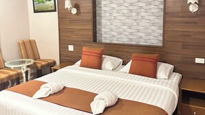 A hotel room with a large bed, a small table, two chairs, a wall-mounted lamp, and a framed picture. - Lenoi Buri (Khuan Khanun)