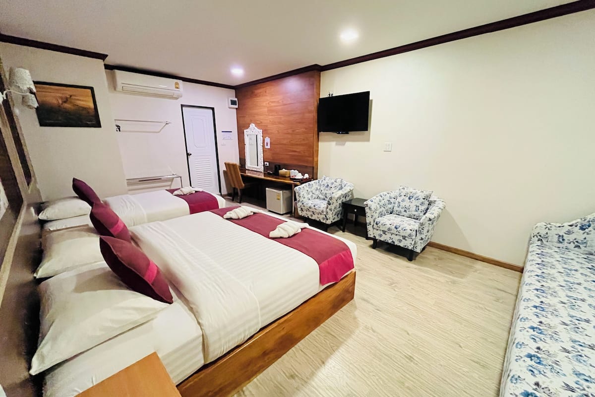 Una habitación de hotel con una cama grande, dos sillones, un escritorio y una televisión.