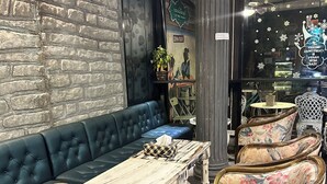 A cozy seating area with a blue sofa, a wooden table, and floral-patterned chairs. - Lenoi Buri (Khuan Khanun)