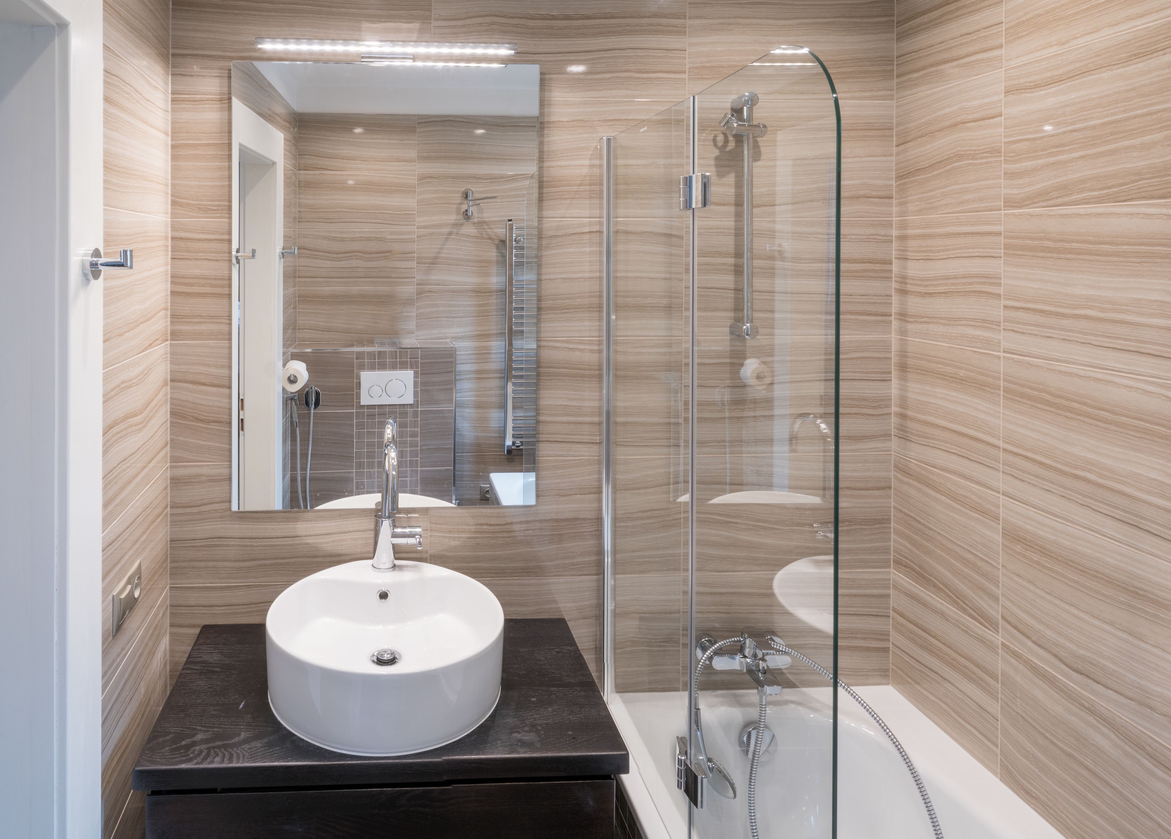 A modern bathroom with a round sink, a glass-enclosed shower, and a mirror above the sink.