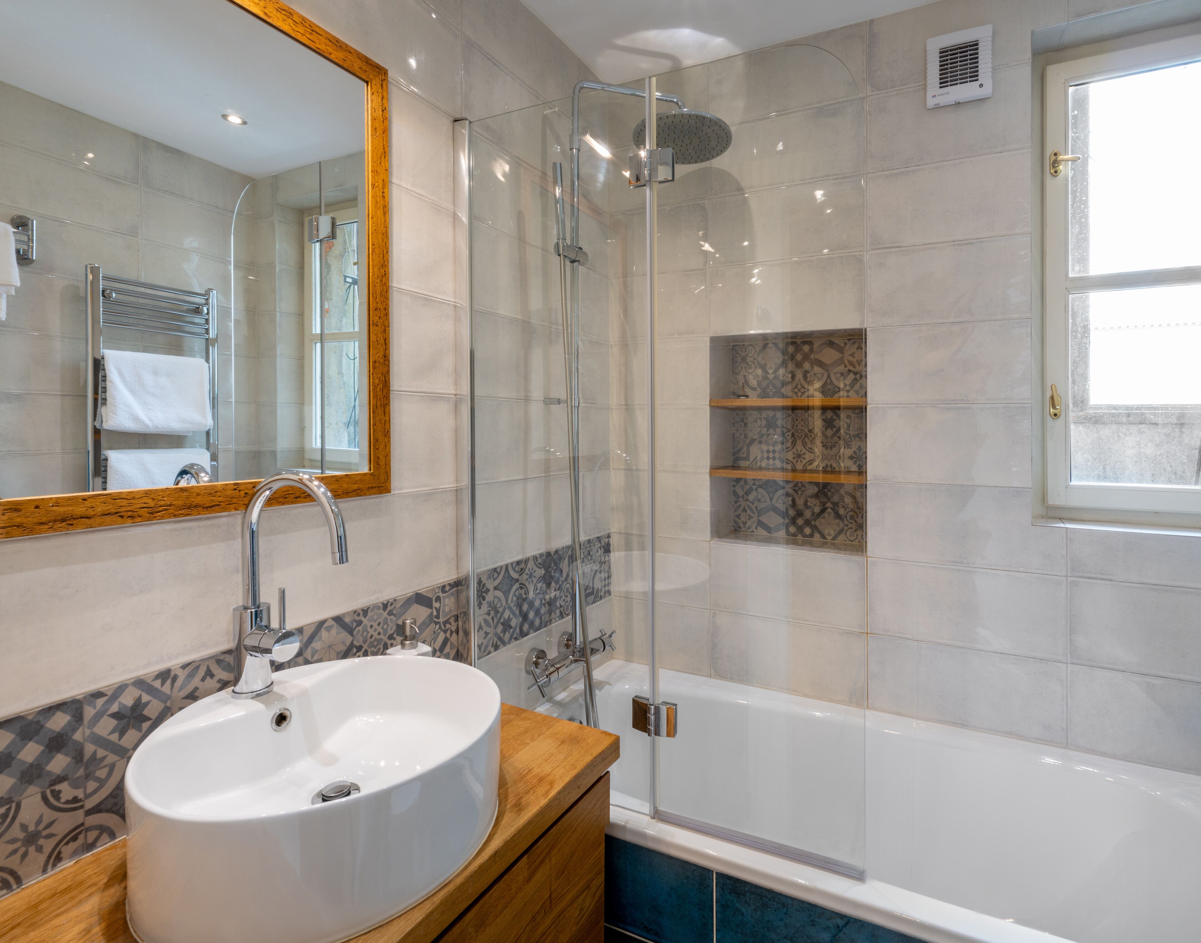 A bathroom with a large mirror, a sink, a shower enclosure, and a bathtub.