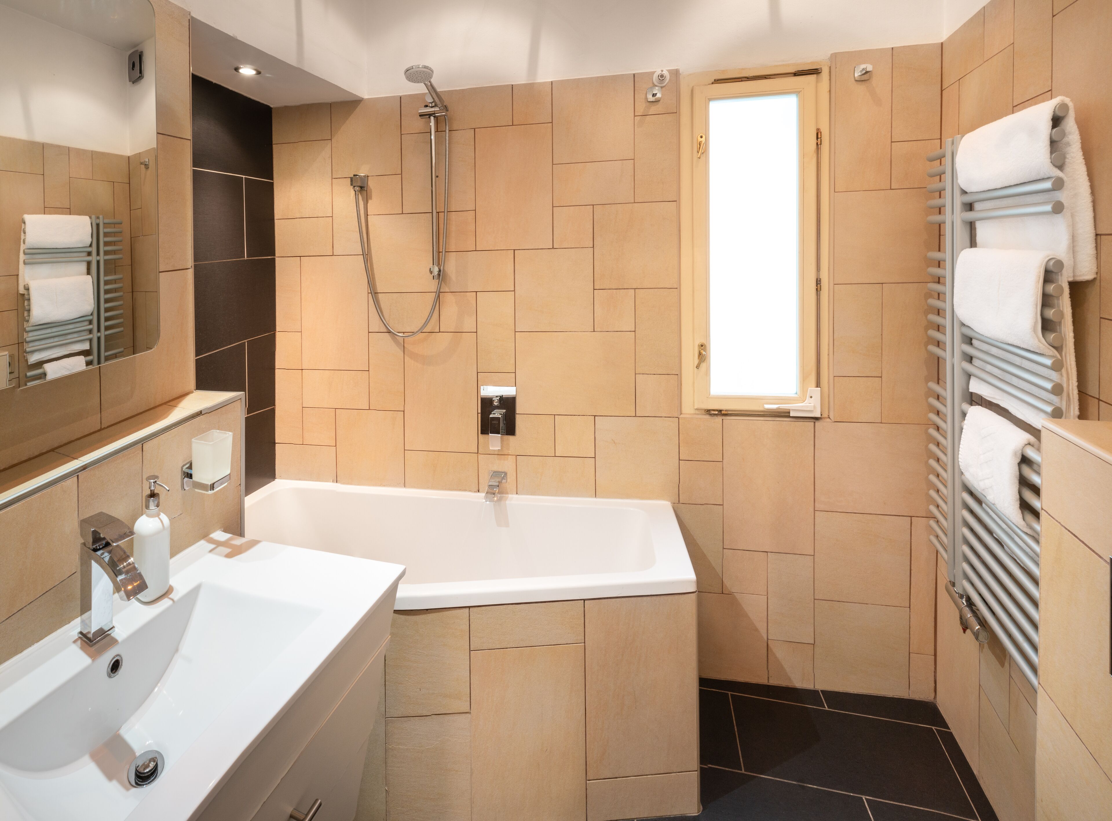 A modern bathroom with a bathtub, a shower, and a large mirror.