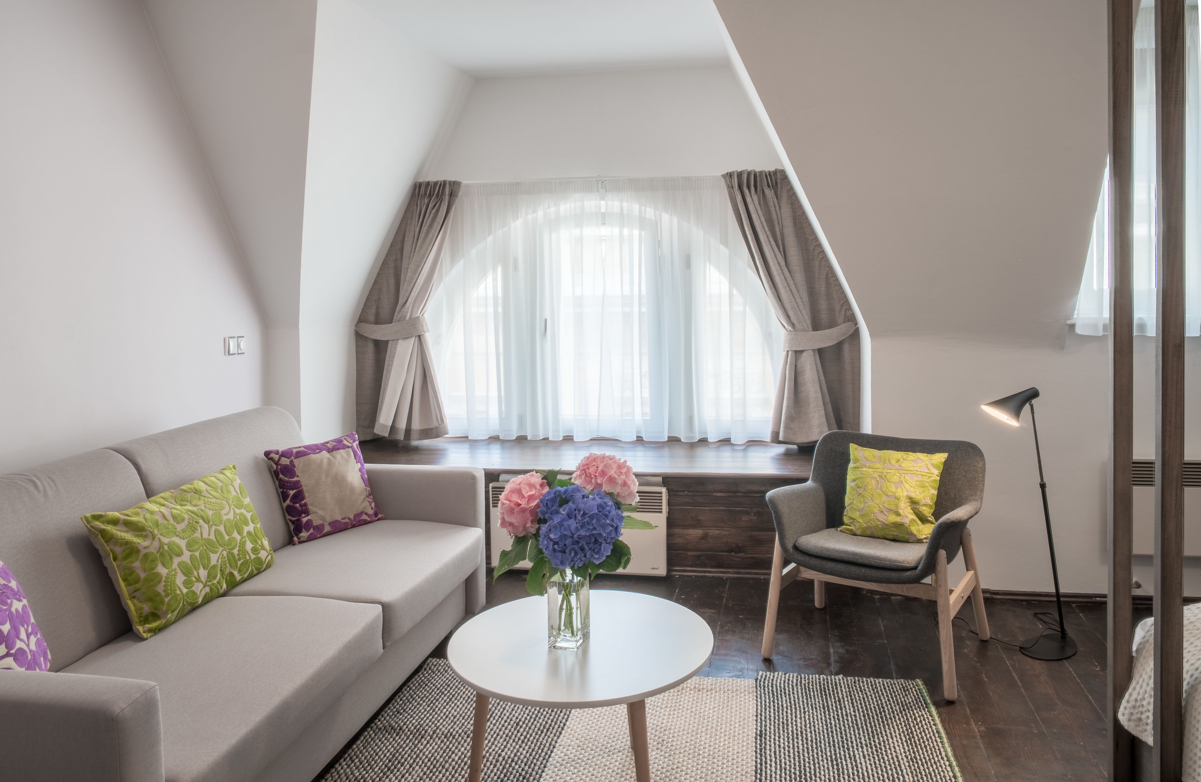 Un salon moderne avec un canapé, un fauteuil et une petite table agrémentée de fleurs.
