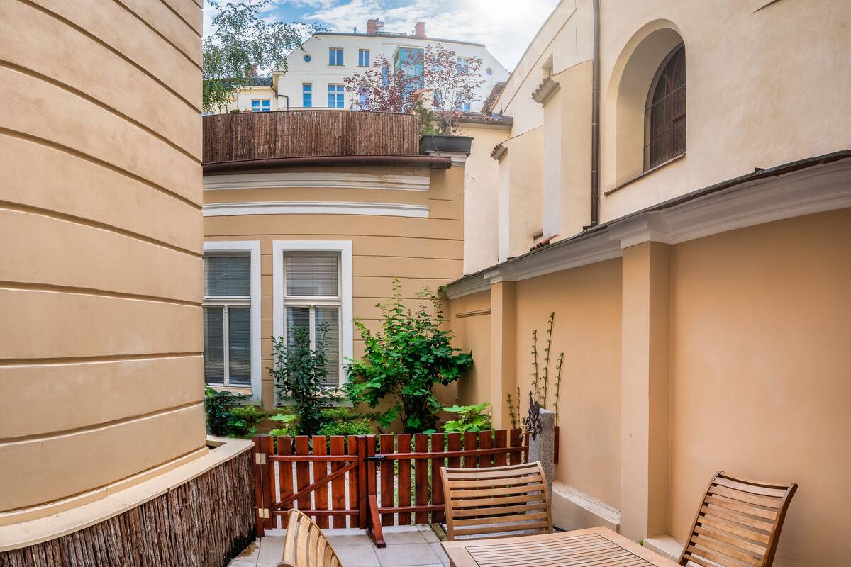 A narrow courtyard with a wooden fence, a small table, and two chairs.