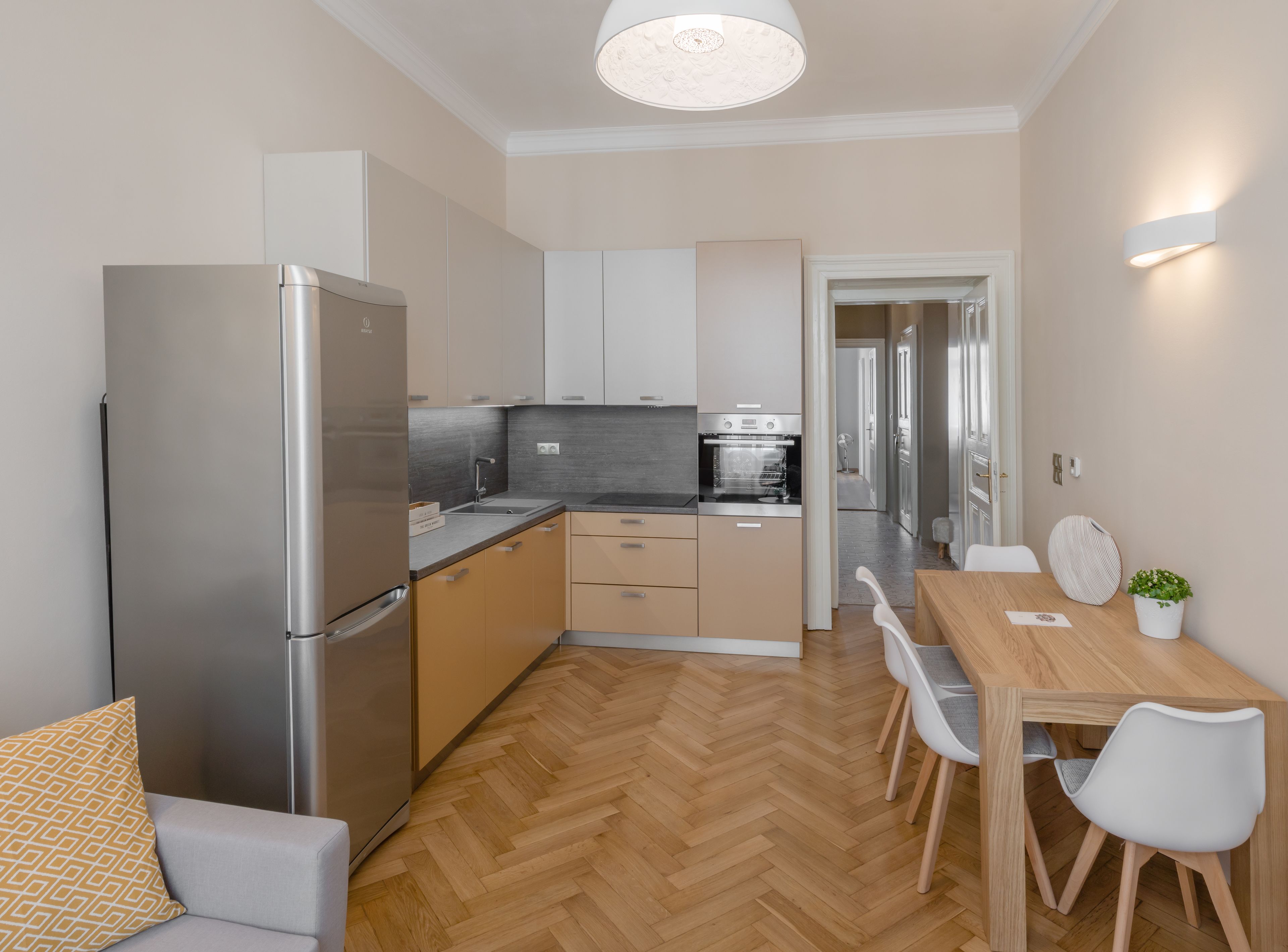 Una cocina moderna con horno empotrado, refrigerador y comedor con mesa y sillas.