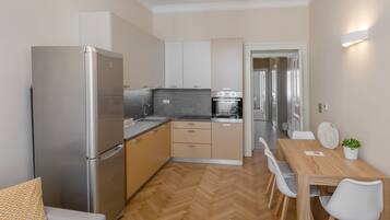 Una cocina moderna con horno empotrado, refrigerador y comedor con mesa y sillas.
