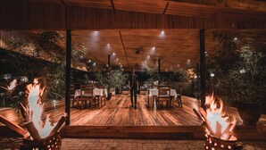 An outdoor dining area with wooden flooring, tables, chairs, and potted plants. - Hemingways Retreat Kigali (Kigali)