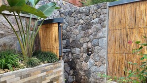 A stone wall with a bamboo fence, a wooden door, and a small wooden platform. - Hemingways Retreat Kigali (Kigali)