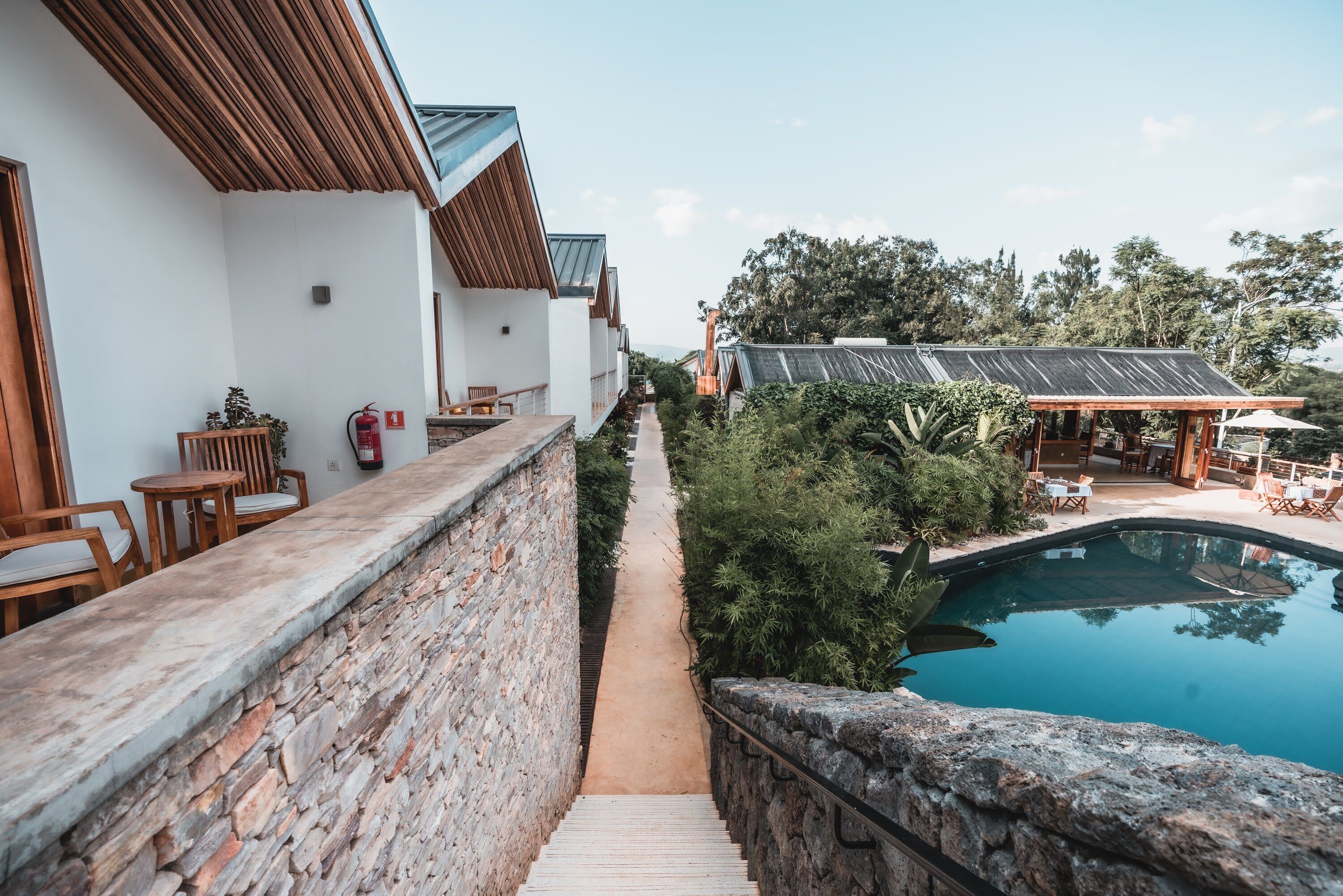 A pool area with a stone wall, wooden deck, and outdoor seating.