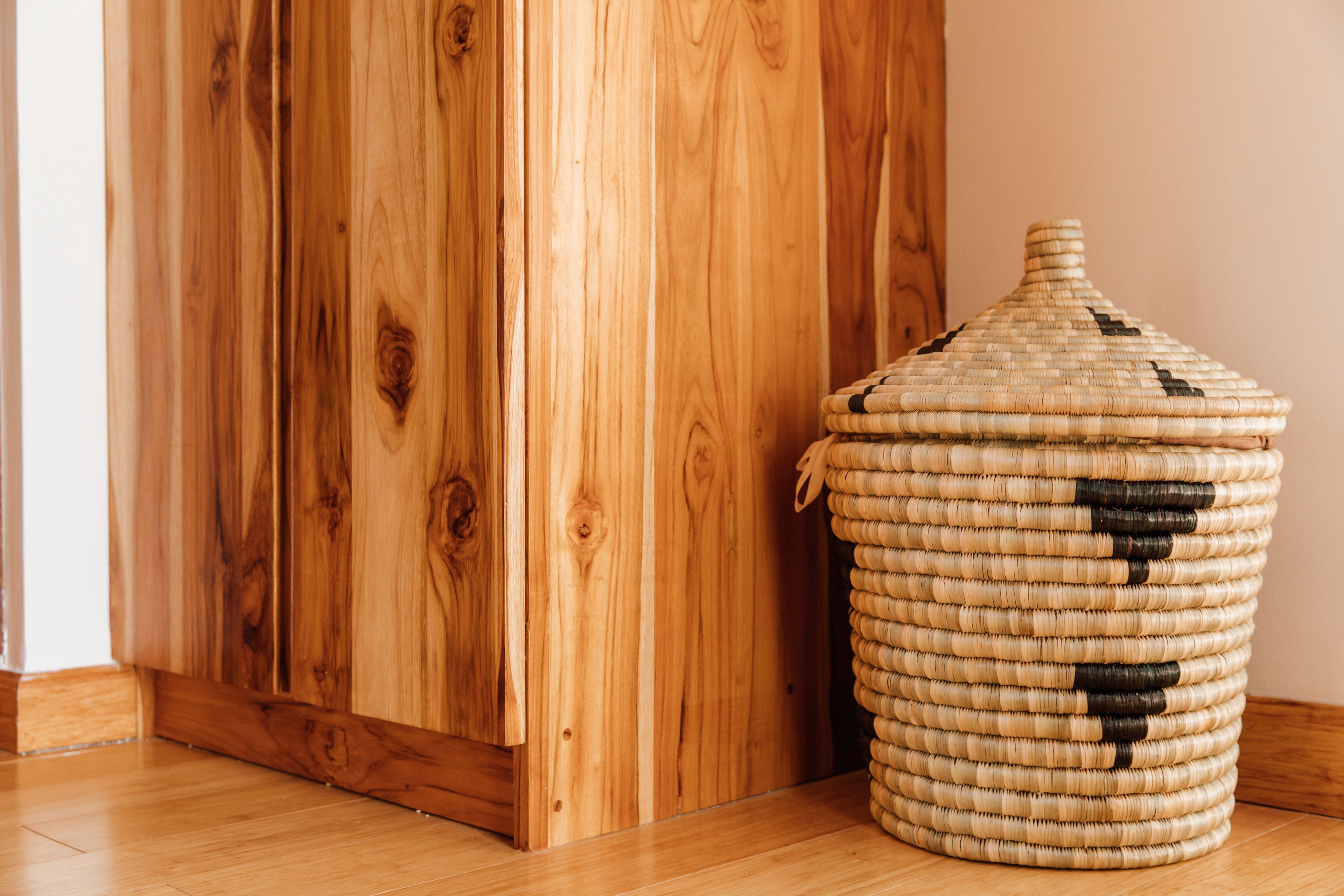 A wooden floor, a woven basket with a lid, and a wooden door.