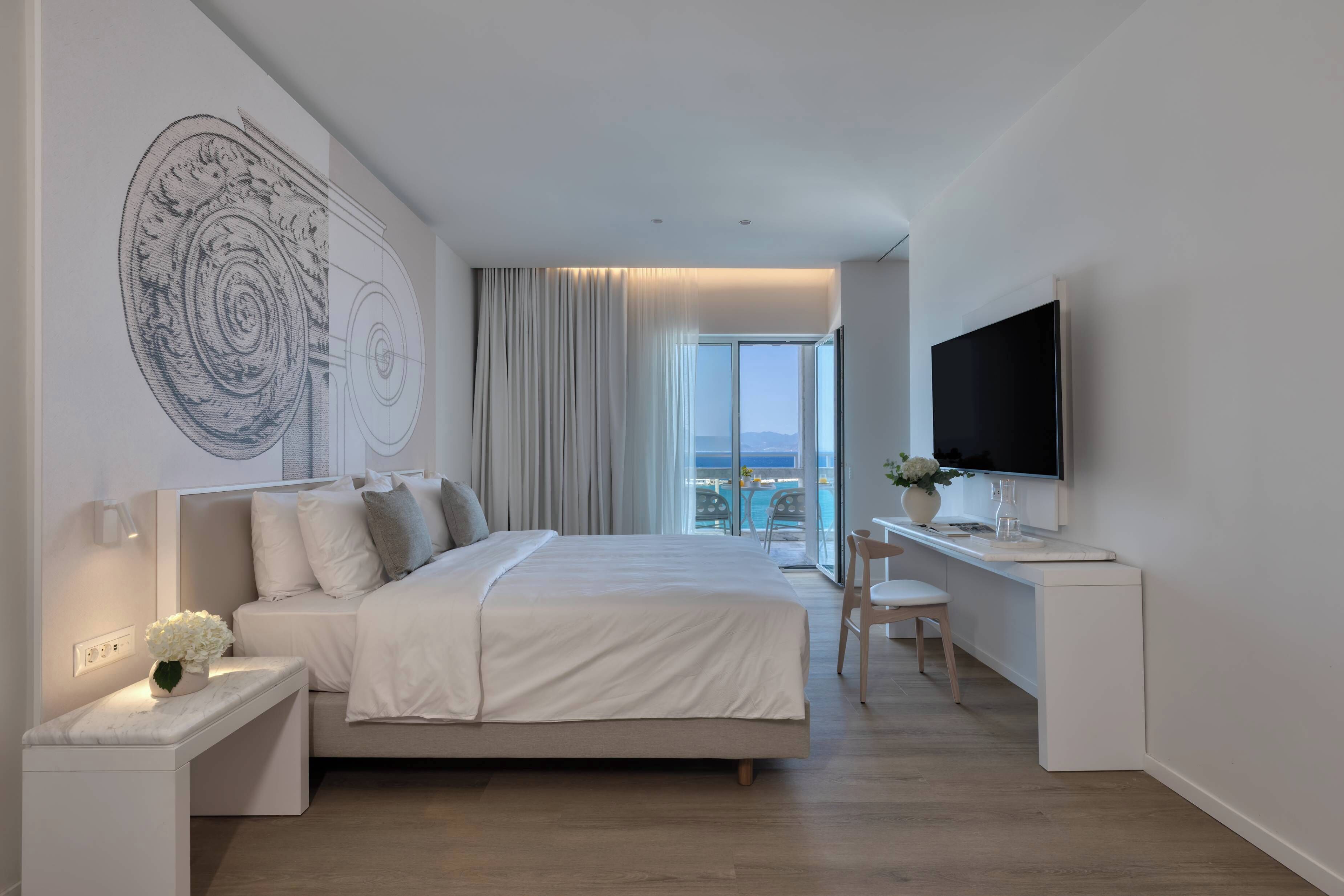 Una habitación de hotel moderna con una cama grande, un escritorio, un televisor de pantalla plana y un balcón con vistas.