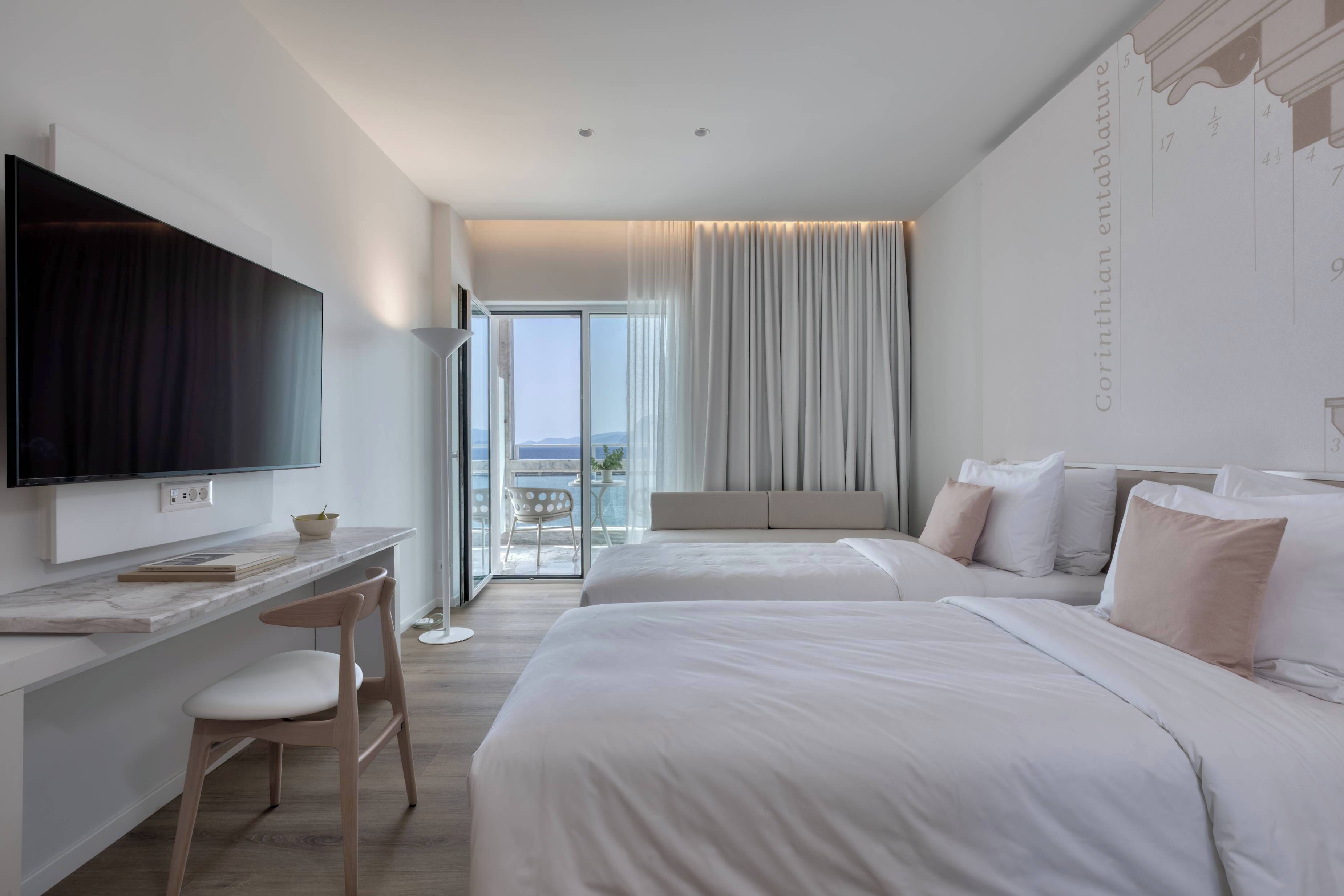 A hotel room with a flat-screen TV, a desk, two beds, and a balcony with a view.